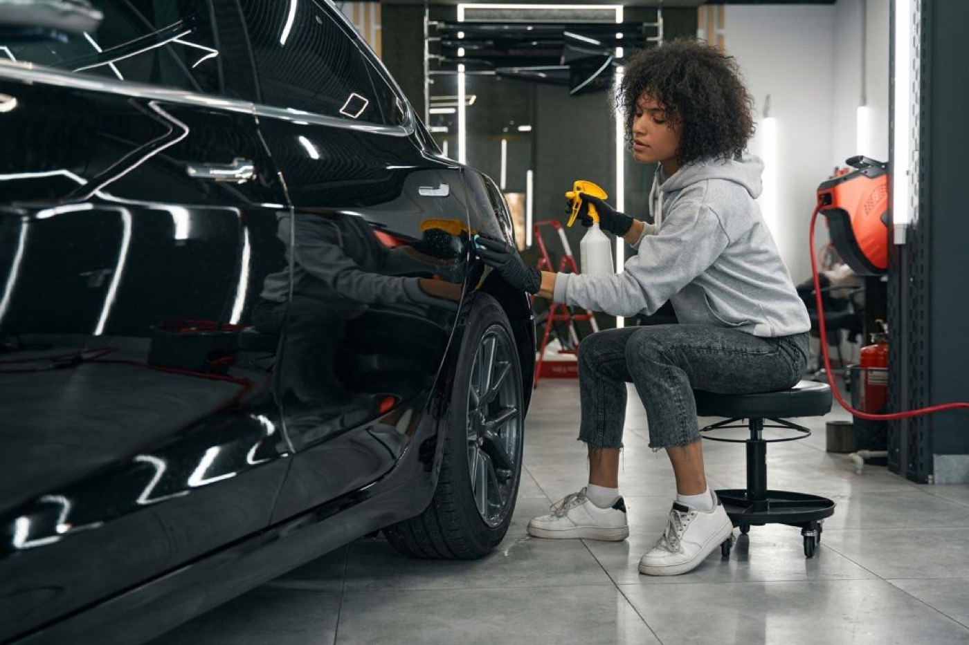Detailer hand-finishing the paint on a black sedan